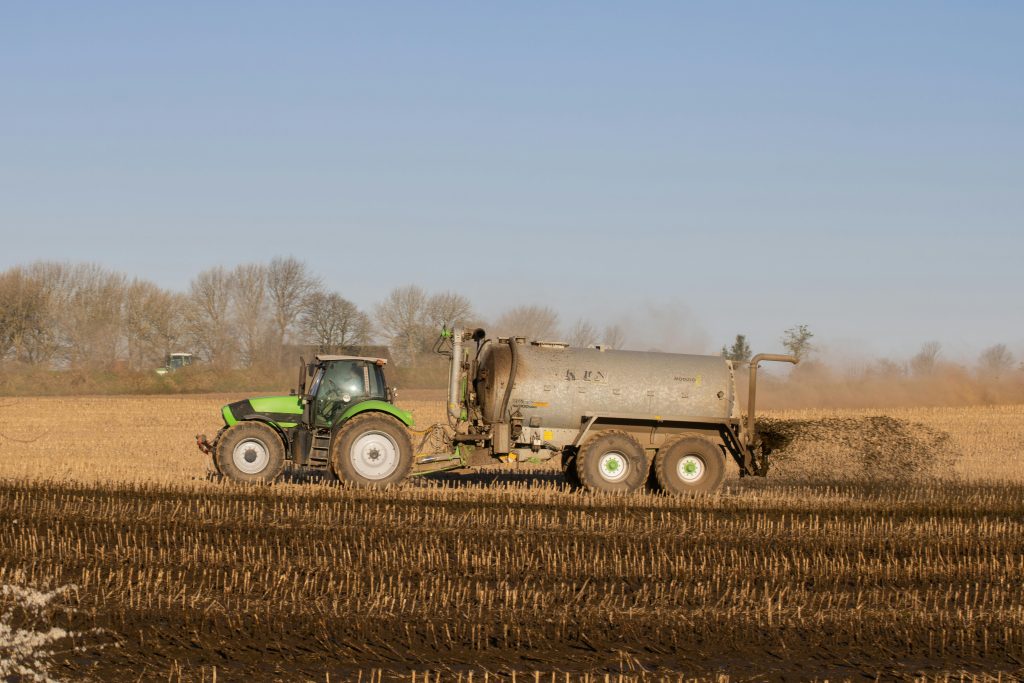 Tractor applying dairy effluent to farmland as part of sustainable soil nutrient management practices in New Zealand