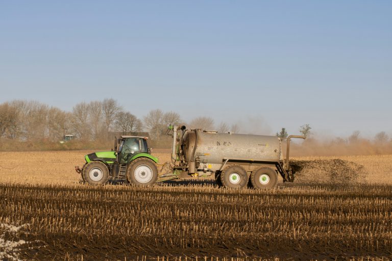 Tractor applying dairy effluent to farmland as part of sustainable soil nutrient management practices in New Zealand